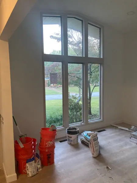 A tall arched window unit in a vaulted wall, with paint and buckets staged below it.