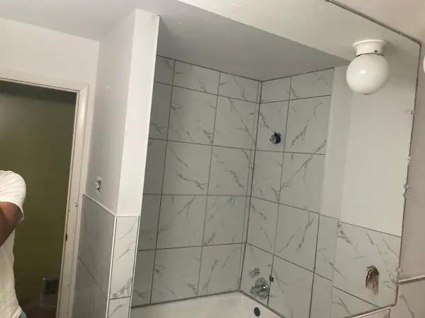 A tub surround mid-tile, spacers still in and the wainscot line carried on around the room.