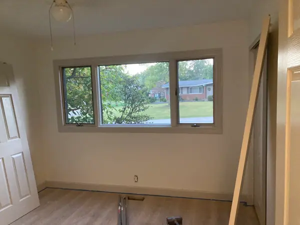 A bedroom with a new three-lite window set and trimmed, and the floor already down.