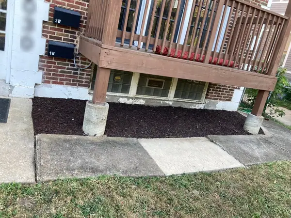 The same strip after: everything cleared out, the bed squared off against the walk and finished in dark mulch around the deck posts