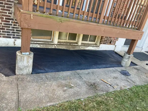 Landscape fabric laid and cut around the deck posts, pinned down and ready for mulch