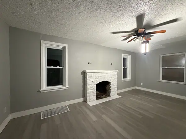 The same room finished: grey walls, white trim, the stone fireplace painted white and wide plank flooring run wall to wall