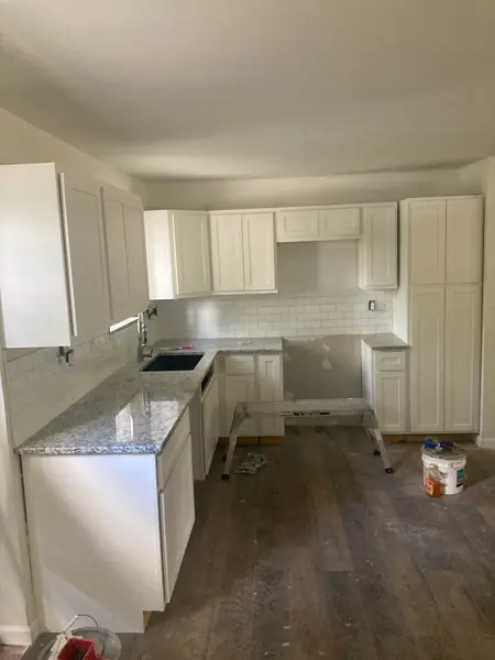Kitchen going back together: cabinets hung, granite tops set, tile splash run, and the gap left for the range.
