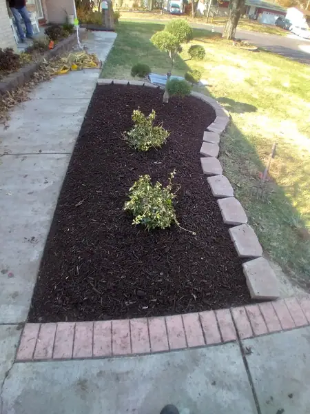A front bed re-cut and edged in brick pavers, fresh mulch down and new shrubs planted along the walk.