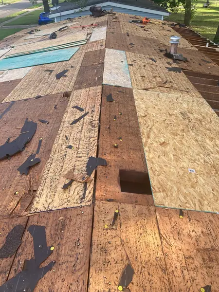 Tear-off in progress across the main slope, with replacement sheathing set in over the worst of the old boards